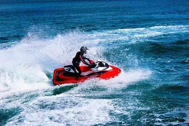 Red jet ski racing with #4 on side and rider with helmet