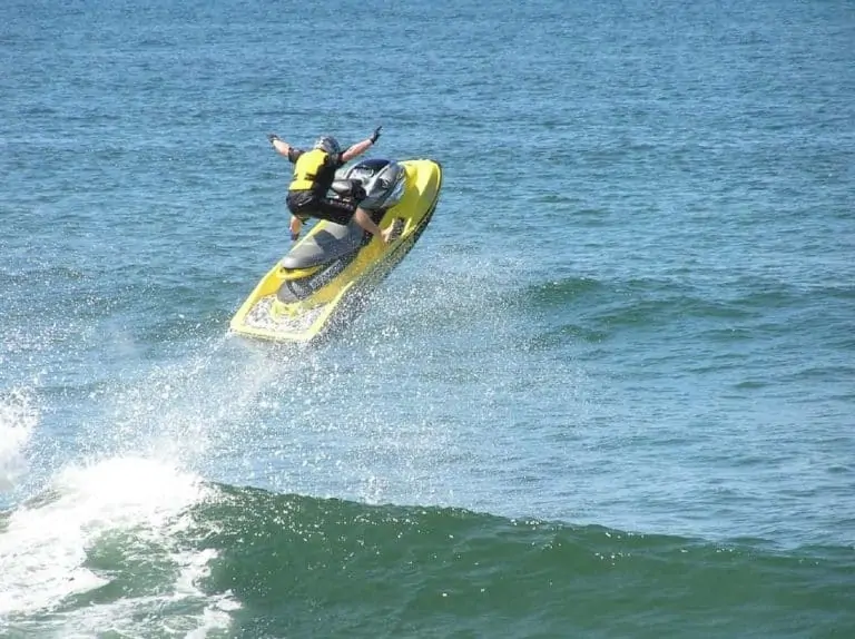 Jet ski jumping ocean wave with rider hands in the air