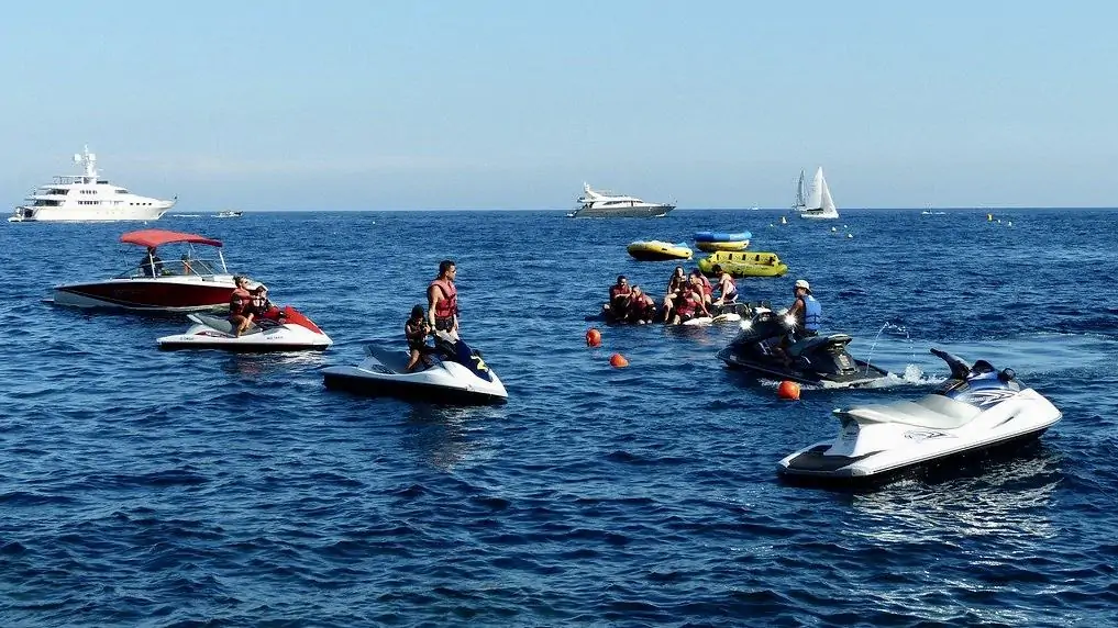 Group of jet skis in ocean with larger boats in distance 